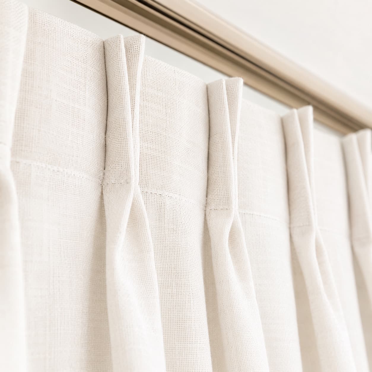 Heading detail on a white linen curtain, folds falling evenly